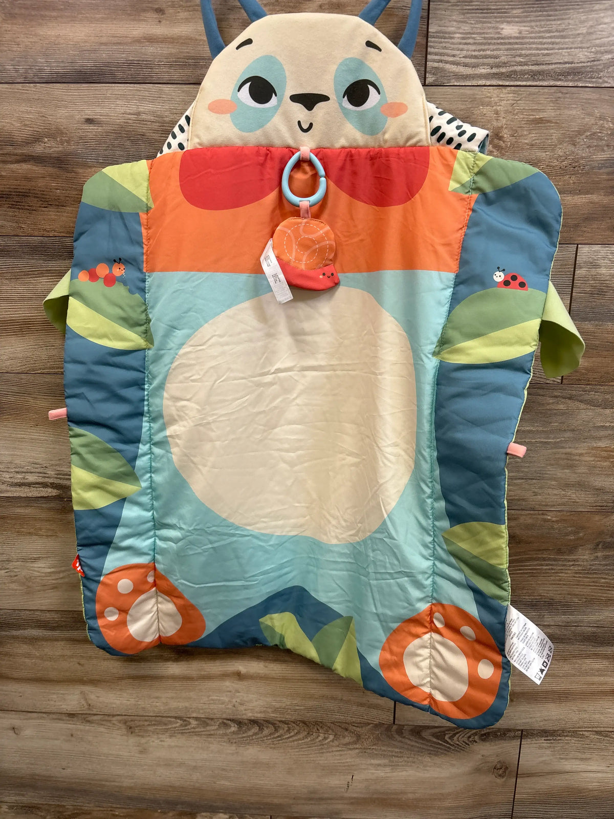 Front view of Fisher-Price Roly-Poly Panda tummy time mat with panda face, hanging toy, and colorful graphics on wood floor