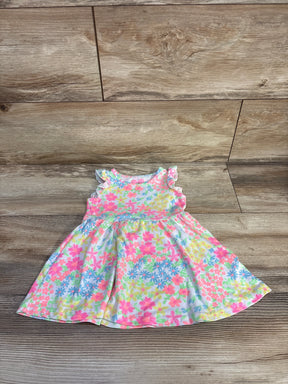 Flat-lay front view of white floral toddler dress (12 months) showcasing ruffled cap sleeves and a gathered skirt on a wood floor background