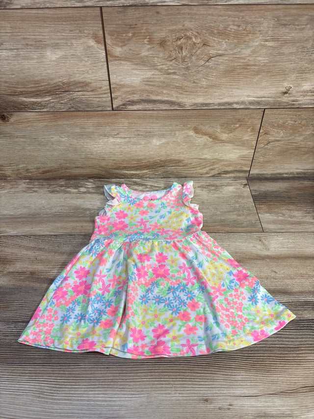 Flat-lay front view of white floral toddler dress (12 months) showcasing ruffled cap sleeves and a gathered skirt on a wood floor background