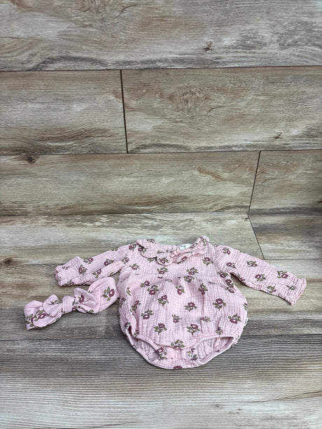 Flat lay of Rabbit and Bear organic two-piece gauze romper and headband set with pink floral print on a wood plank background