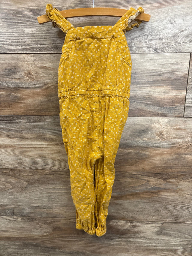 Mustard yellow baby romper with white dot pattern, adjustable straps, hanging on wood hanger for kids clothing resale