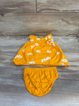 Flat lay of yellow baby dress and bloomers showing white floral print and ruffled sleeves on wood background