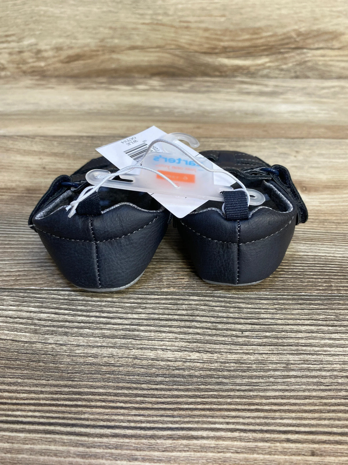 Navy blue baby shoes with tags on wood background, children's footwear resale item