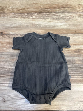 Flat lay of Modern Moments organic dumpling romper in dark grey ribbed knit with short sleeves and snap closures on wood plank floor