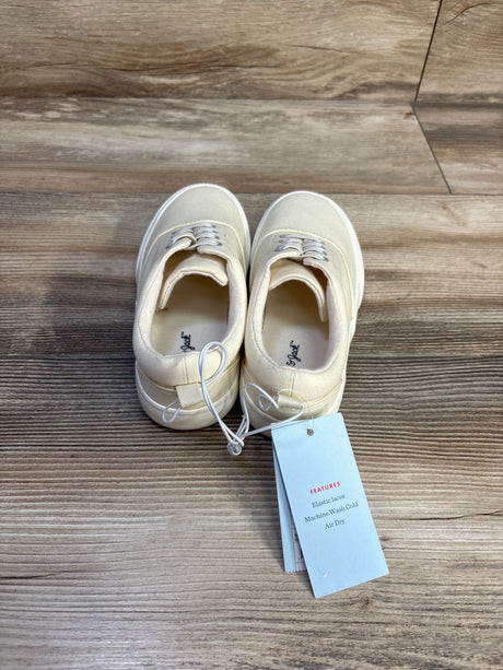 Top view of Cat & Jack toddler slip-on sneakers, off-white size 13C, showing elastic laces and tag on wood background