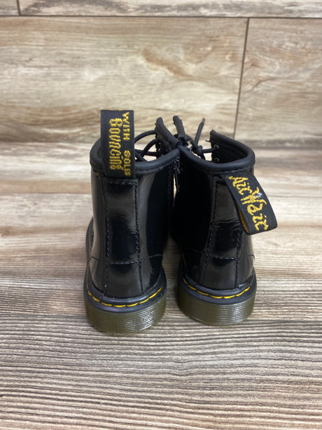 Rear view of Dr. Martens 1460 black boots showing yellow stitching and pull tabs on a wood floor