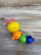 Angled overhead view of Baby Einstein Twist-a-Pal Cal showcasing four colorful connected bead segments and attached teether ring on wood surface