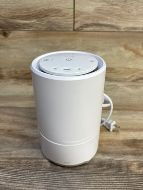 Front view of Frida Baby 3-in-1 air purifier sound machine and nightlight showing top touch controls and power cord on wood background