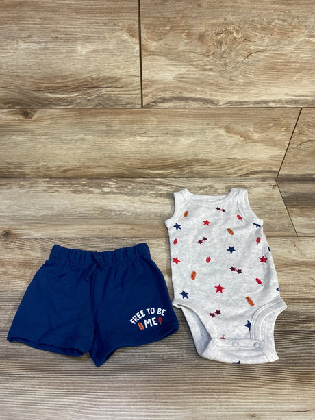 Top-down view of 2-piece baby set: grey bodysuit with star and popsicle print, navy shorts reading 'Free to be me' on wood
