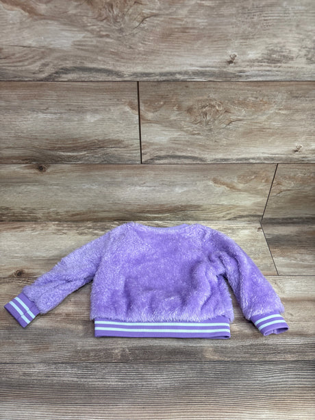 Purple plush baby sweatshirt with white striped cuffs and waistband on a wood background.