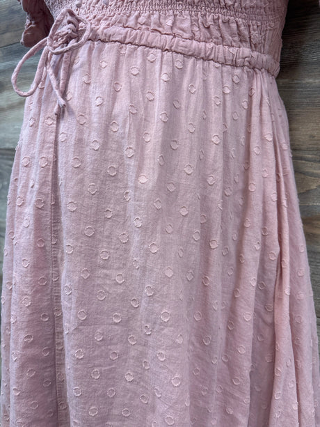 Close-up of pink R.YIposha bump-friendly smocked flowy dress showcasing textured dot fabric and waist tie on a wood surface