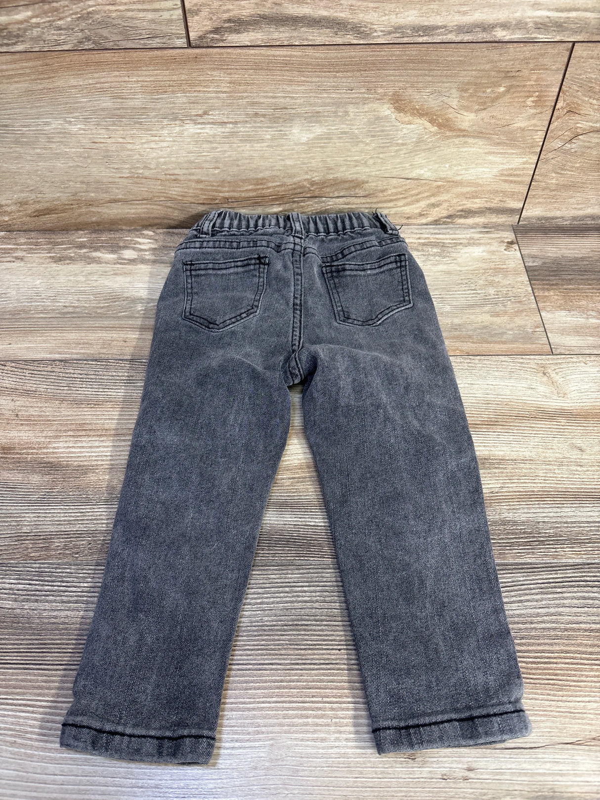 Back view of grey toddler jeans size 2T showing elastic waistband and back pockets laid flat on wood surface