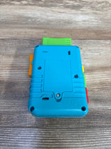 Rear view of Fisher-Price Laugh & Learn Lil' Gamer showing blue battery compartment and colored side buttons on wood tabletop