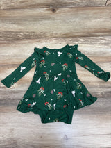 Front view of Kyte Baby Mistletoe Twirl Bodysuit Dress in green with long sleeves, ruffled skirt, and attached bodysuit on wood