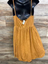 Front of Boohoo mustard yellow maternity sleeveless dress with spaghetti straps and gathered empire waist on wood background