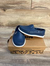 Navy blue slip-on kids shoes with white soles on a recycled shoebox, wood background