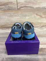 Rear view of Pediped Dani crib shoes showcasing stitched heel pull-tab and soft sole with purple shoebox and wood background