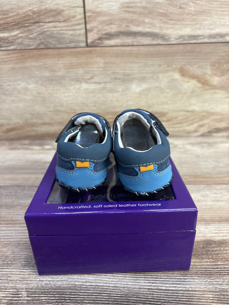 Rear view of Pediped Dani crib shoes showcasing stitched heel pull-tab and soft sole with purple shoebox and wood background