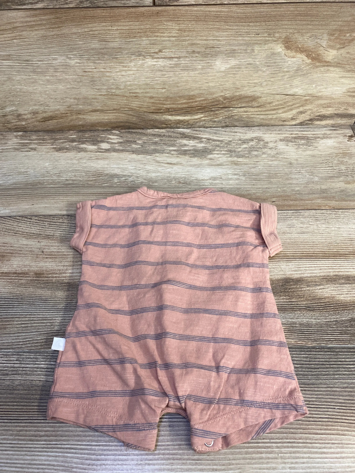 Back view of Little Planet organic striped shortie romper in muted orange showing navy horizontal stripes and snap crotch on wood background