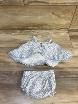 Flat lay of Rabbit Bear organic 2-piece blue floral tank top with wooden buttons and ruffle trim, and matching elastic-waist bloomers on wood surface