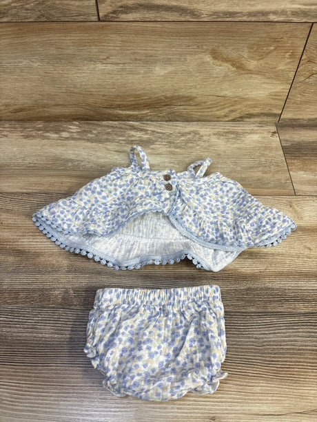 Flat lay of Rabbit Bear organic 2-piece blue floral tank top with wooden buttons and ruffle trim, and matching elastic-waist bloomers on wood surface