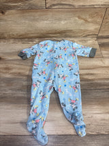 Flat-lay of blue Mickey Mouse footed sleeper showing all-over Mickey print and gray cuffs on wood background