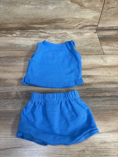 Flat lay of newborn blue tank top and elastic-waist shorts set showing ribbed knit texture on wood floor background