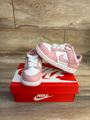 Front and side of toddler Nike Dunk Low Pink Glaze sneakers showing pink overlays, perforated white toe, Swoosh on red box