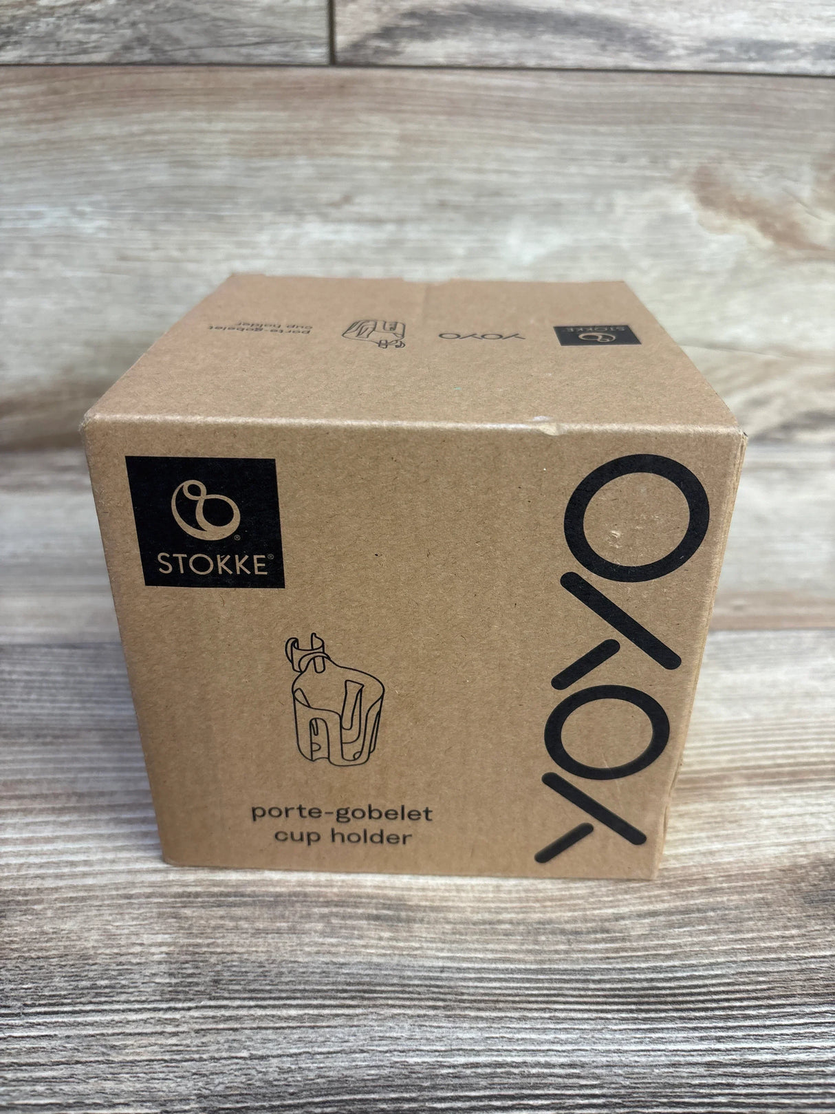 Front view of Stokke Yoyo cup holder box showing printed Yoyo logo and product sketch on wooden tabletop background