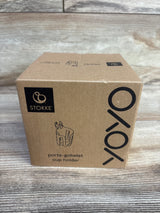 Front view of Stokke Yoyo cup holder box showing printed Yoyo logo and product sketch on wooden tabletop background