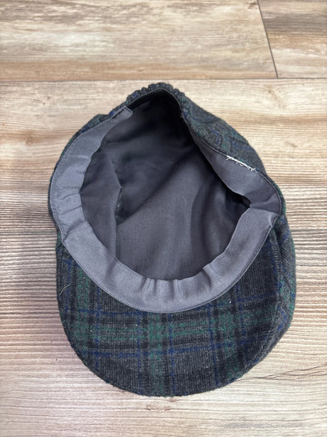 Underside view of grey tartan plaid wool newsboy cap showcasing dark lining with a wood surface background