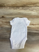 Back view of newborn white Nike bodysuit showing short sleeves and snap closure at the crotch on wood plank background
