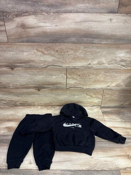 Top view of black Nike two piece pullover sweatshirt and joggers set showcasing hood, front pocket, and elastic cuffs on wood flooring