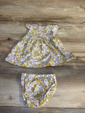 Floral baby dress and bloomers set with purple, yellow, and green print on wood background