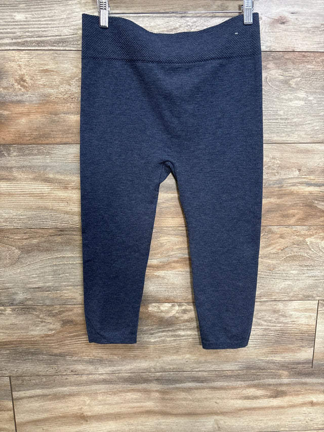 Front view of blue maternity leggings showing textured high waistband and ankle-length legs on wood plank background