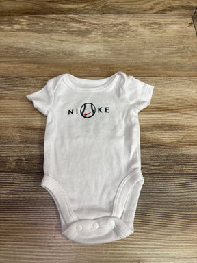 White Nike newborn bodysuit with a baseball graphic on the chest, lying on a wooden surface.