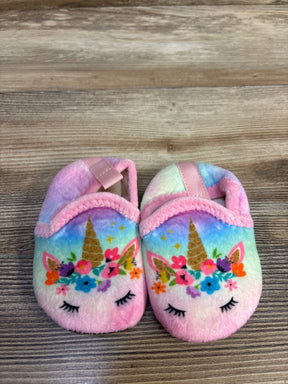 Top view of pink baby unicorn slippers, size 5C, with floral faces, gold horns and elastic straps on wood background