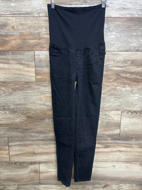 Front view of Monkey Ride maternity black jeans with high stretch belly panel and slim tapered legs against wood background