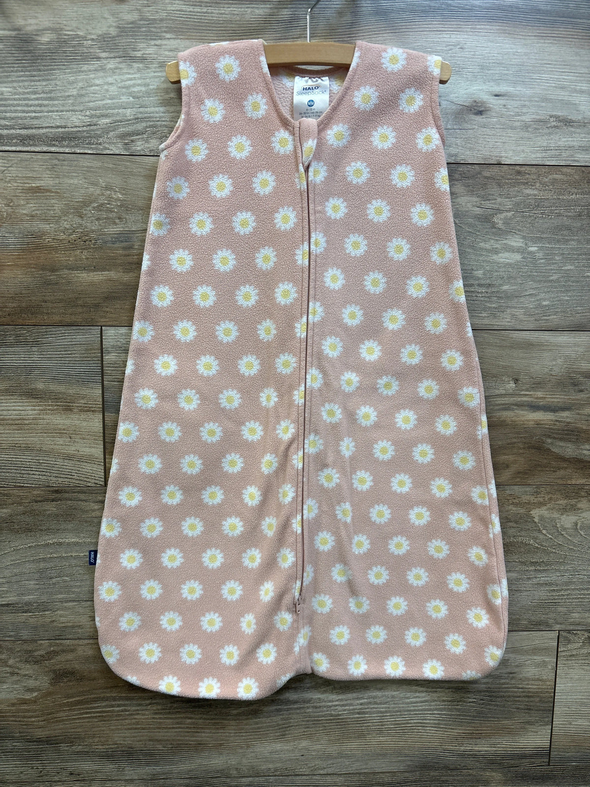 Front view of pink Halo SleepSack blanket for 6 to 12 months showcasing daisy print and front zipper on a wooden background