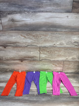 Flat lay of four 18-month toddler leggings in orange, purple, green, and pink showing full-length legs on wood plank background