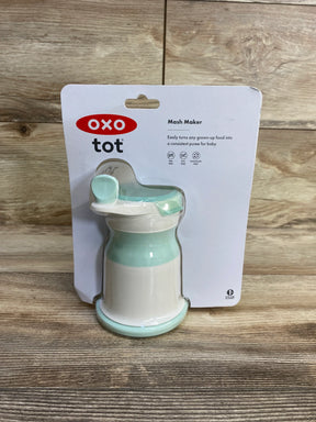 Front view of OXO Tot Mash Maker showcasing opal mint lid and mash mechanism on wood background