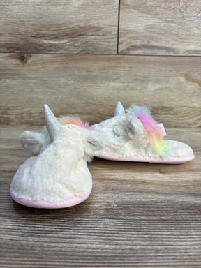 Fluffy unicorn slippers for kids with rainbow mane, silver horn, and pink sole on wood floor