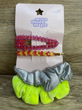 More Than Magic hair accessory set with pink and yellow beaded clips and neon green and silver scrunchies on wood surface