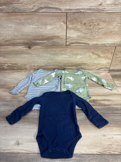 Front view of three Carter's long-sleeve baby bodysuits (size 3M) showing navy solid, gray stripe, and sage dinosaur print on wood background