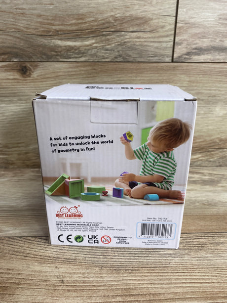 Box of Best Learning geometry blocks with child in green striped shirt playing on wooden floor