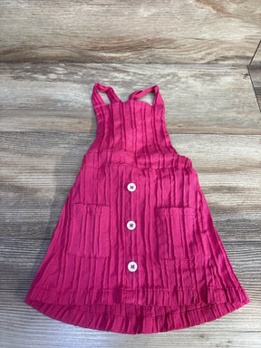Flat-lay pink toddler skirtall (12-18 months) showing crinkled texture, three white buttons and two front pockets on wood background