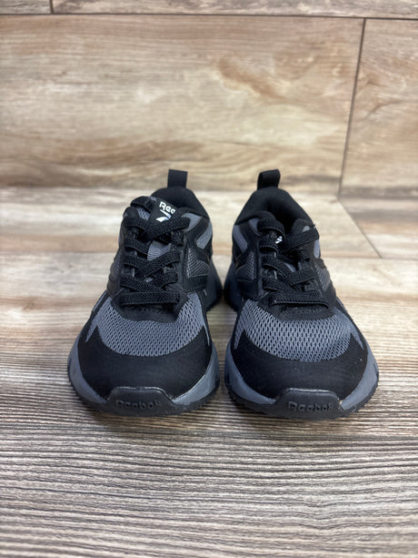 Front view of Reebok Charge Run sneakers in black, size 6C, showcasing mesh uppers and laces with a wood-look floor background