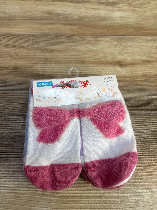 Top-down view of Nuby 10-pack baby socks showing fuzzy pink bow design and pink toe caps on a wooden surface, size 12-24 months
