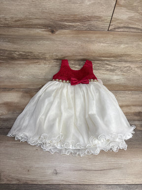 Baby girl's sleeveless dress with red lace top, bow, and white layered tulle skirt on wooden floor