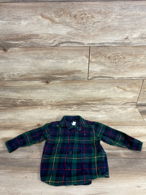 Children's long-sleeve green and navy plaid button-up shirt laid flat on wood floor